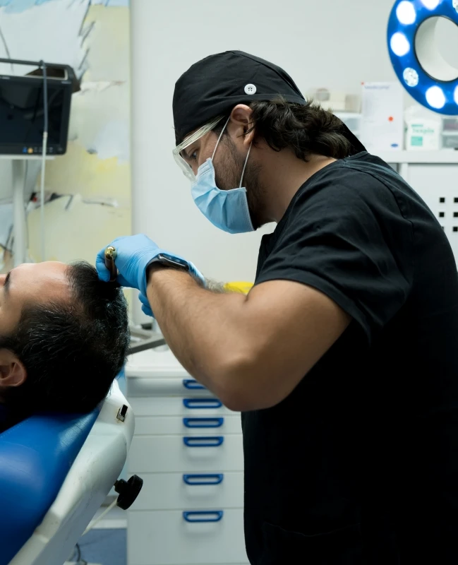 Doctor del equipo medico de Kuntur Clinic en quirofano realizando tratamiento capilar a paciente en la ciudad de Barcelona